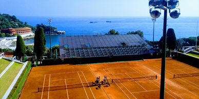Two people playing tennis on a clay court.